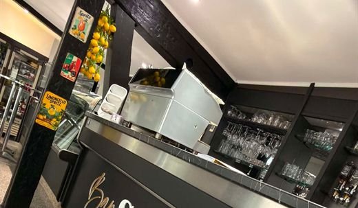 Detail der Theke: die Espressomaschine hinter der Marmorplatte, links eine Girlande aus Zitronen und Schilder für Spritz und Limoncello, rechts das Glasregal.